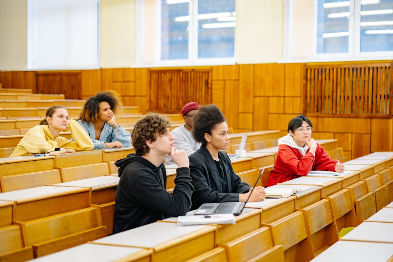 Offerings Students of various backgrounds attentively listening in a university lecture hall.